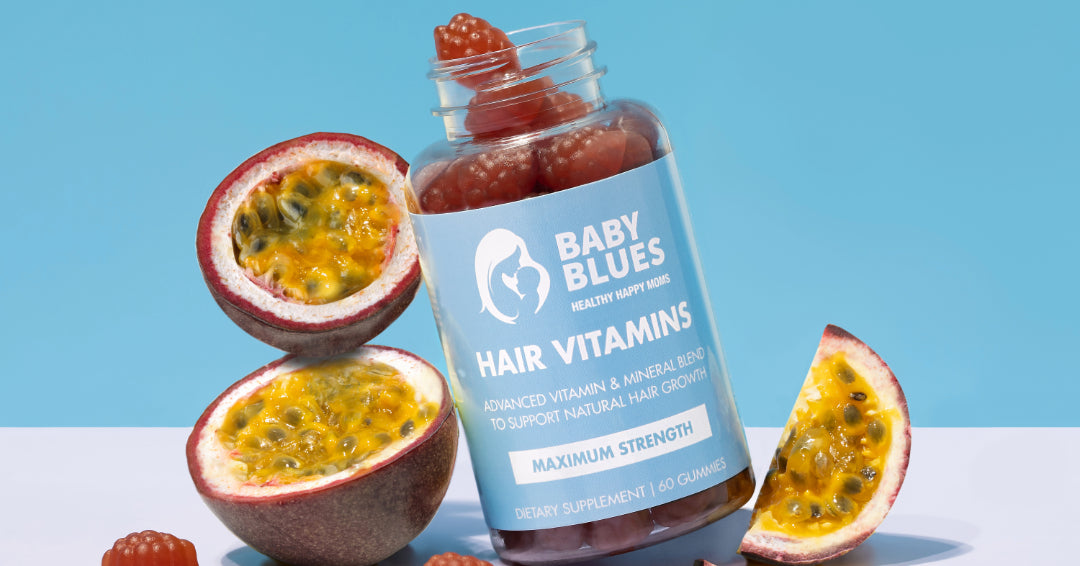 Baby Blues Hair Vitamins bottle with gummies displayed beside fresh passion fruit on a bright blue background.