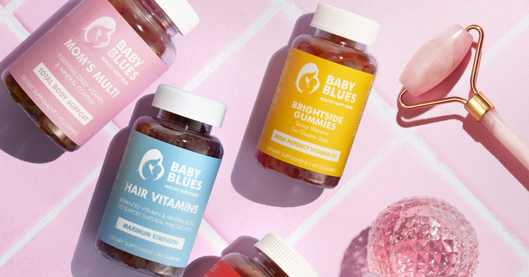 Baby Blues Hair Vitamins, Mom’s Multi, and Brightside Gummies displayed on pink tiles with a rose quartz roller.