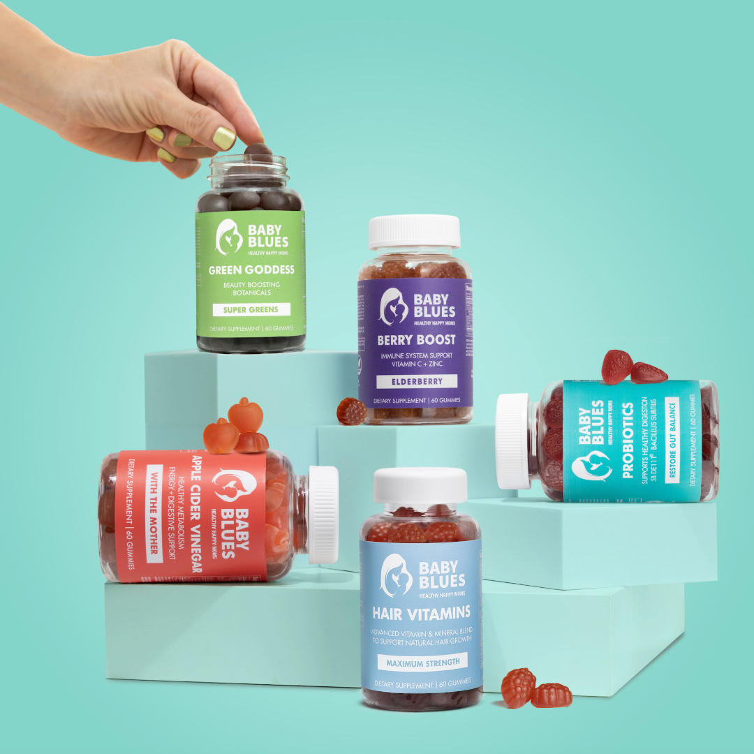 Collection of Baby Blues supplement bottles arranged on pastel stands showcasing hair, boost, and probiotic vitamins.
