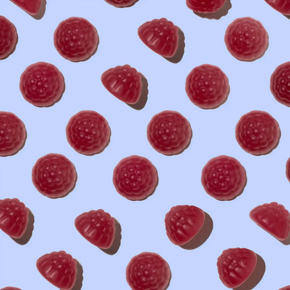 Pattern of red gummy raspberries shaped gummies on a light blue background
