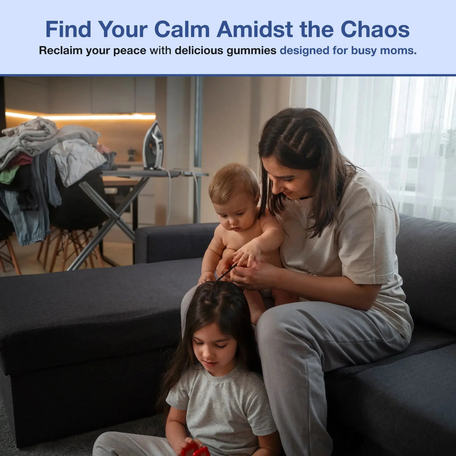 Mom with two kids, one sitting and the other standing, playing amidst a cluttered home environment