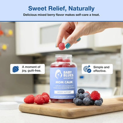 Hand reaching for a mixed berry-shaped gummy from Baby Blues Mom Calm bottle, with berries on the table.
