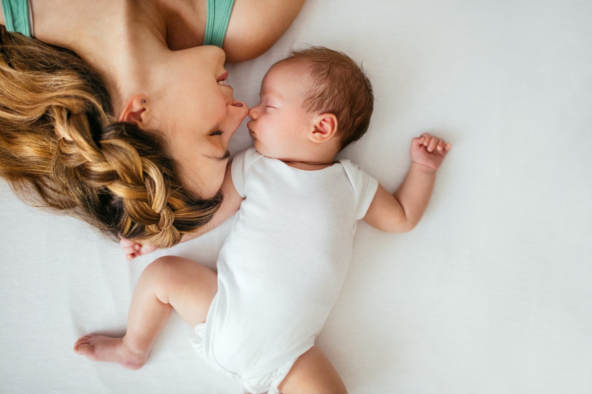 Mother and baby bonding while lying side by side, smiling and resting together.
